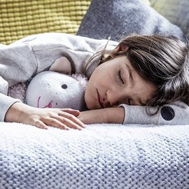 Ein Maedchen mit einem Kuscheltier im Arm, schlaeft